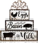 A set of four black and white wooden farmhouse signs, featuring a cow, rooster, and pig, displayed on a tiered tray.