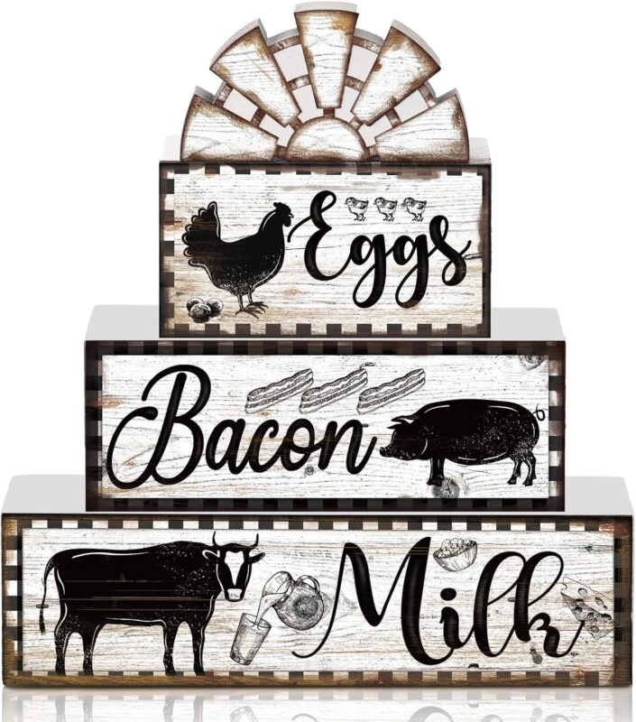 A set of four black and white wooden farmhouse signs, featuring a cow, rooster, and pig, displayed on a tiered tray.