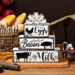 A set of four black and white wooden farmhouse signs, featuring a cow, rooster, and pig, displayed on a tiered tray.