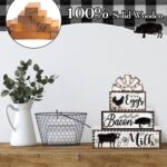 A set of four black and white wooden farmhouse signs, featuring a cow, rooster, and pig, displayed on a tiered tray.