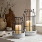 Two KIBAGA rustic farmhouse lanterns, one large and one small, with distressed black and white finishes, on a tabletop.