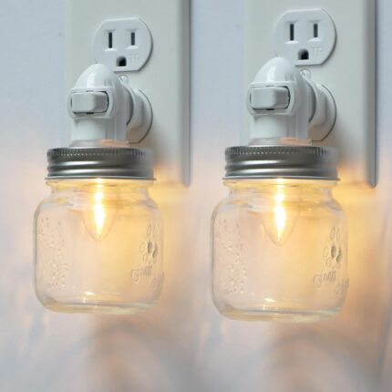 Two clear glass Mason jar night lights with brushed plastic bases, plugged into wall outlets, emitting a warm glow.