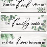 Three Maitys eucalyptus greenery wooden wall signs with 'Bless Family Food Love' text, hung on a rustic wall.