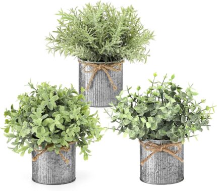 Three small artificial plants: eucalyptus, boxwood, and rosemary, each in a grey galvanized metal pot with a jute rope bow, a