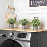 Three small artificial plants: eucalyptus, boxwood, and rosemary, each in a grey galvanized metal pot with a jute rope bow, a