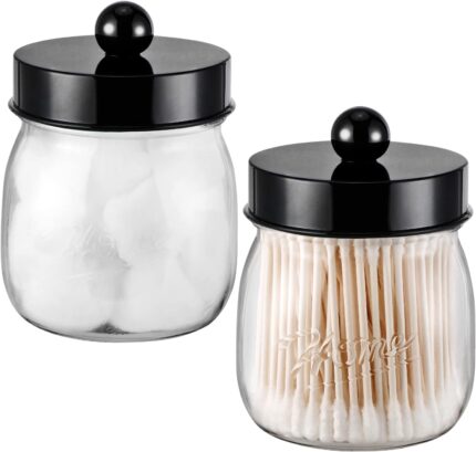 Two black acrylic mason jar qtip holders with lids and labels, displayed on a bathroom counter.