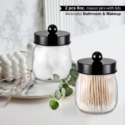 Two black acrylic mason jar qtip holders with lids and labels, displayed on a bathroom counter.